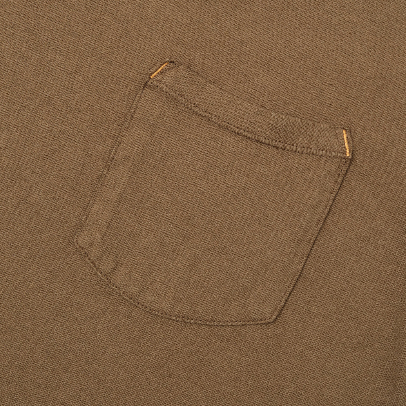 Close-up of brown cotton fabric with a single stitched pocket and reinforced orange stitching at the top corners