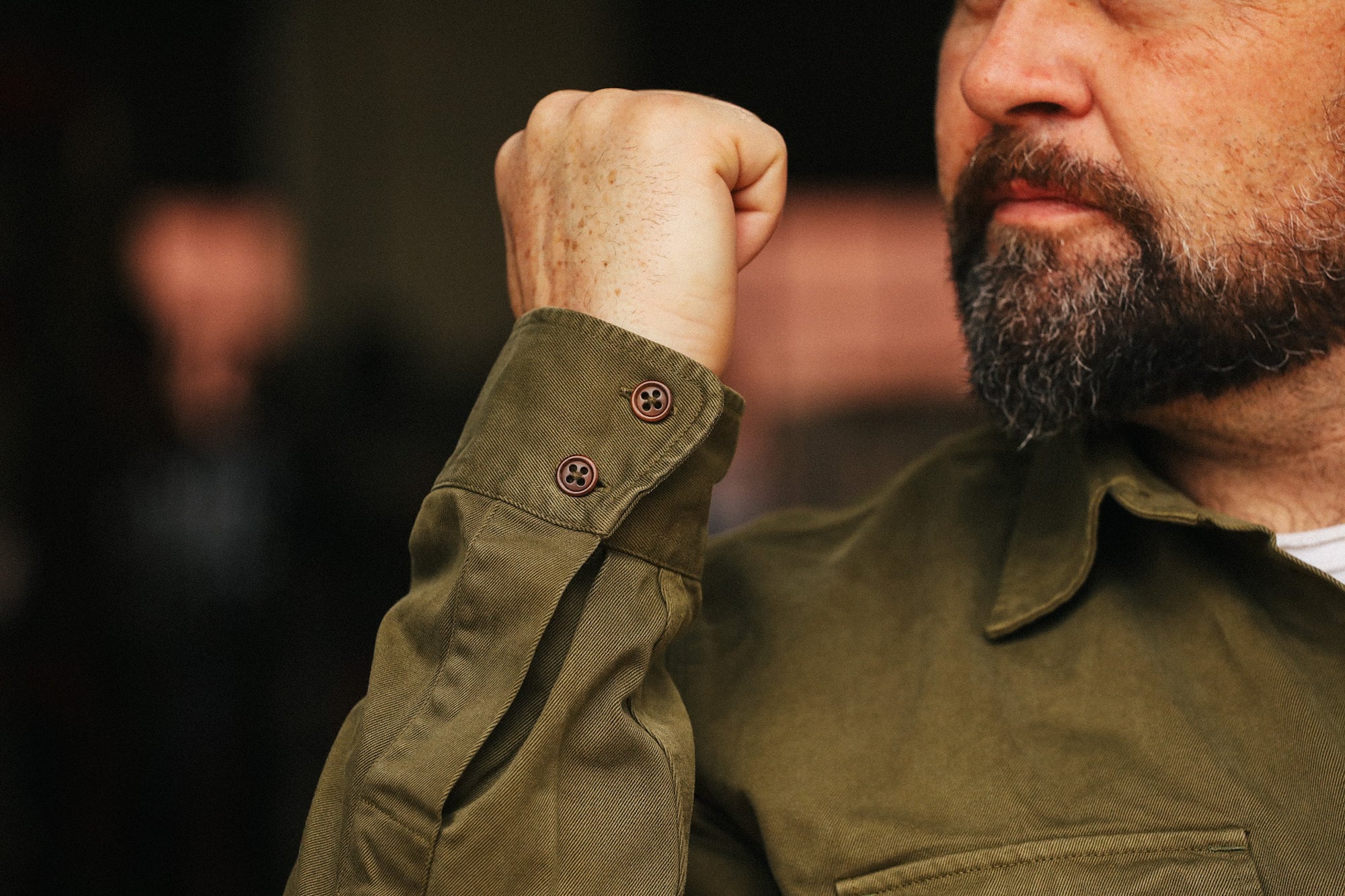 Man in a green shirt with his fist raised, blurred background