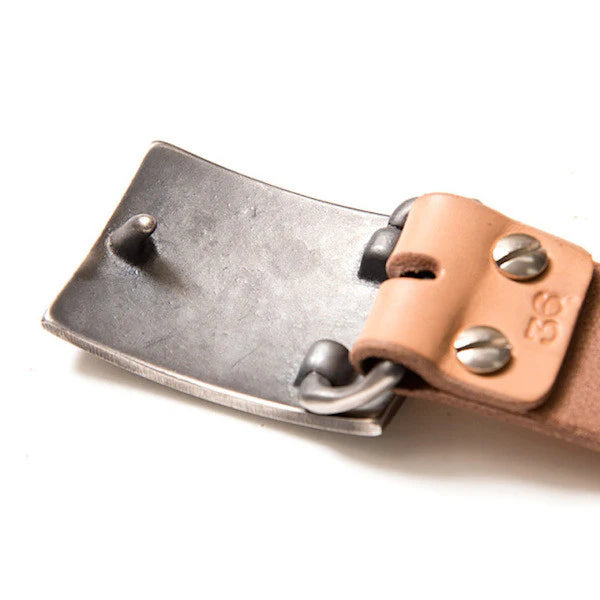 Close-up of iron belt buckle with tan leather strap and industrial rivets from Iron Shop Provisions