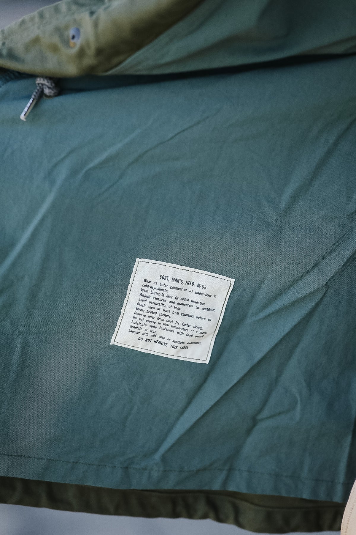 Green jacket with a label on a neutral background