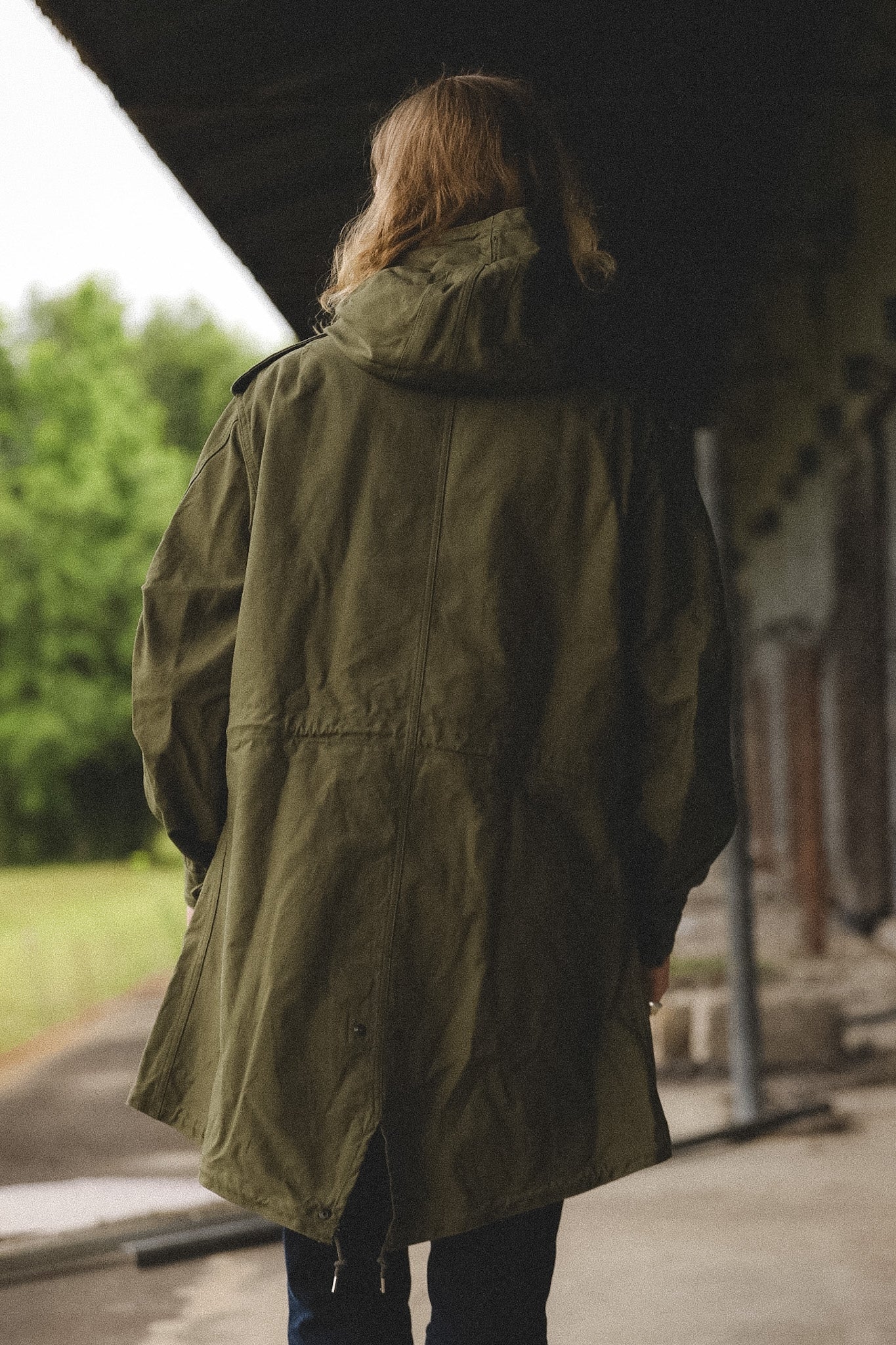 Person wearing a green coat standing outdoors with blurred background