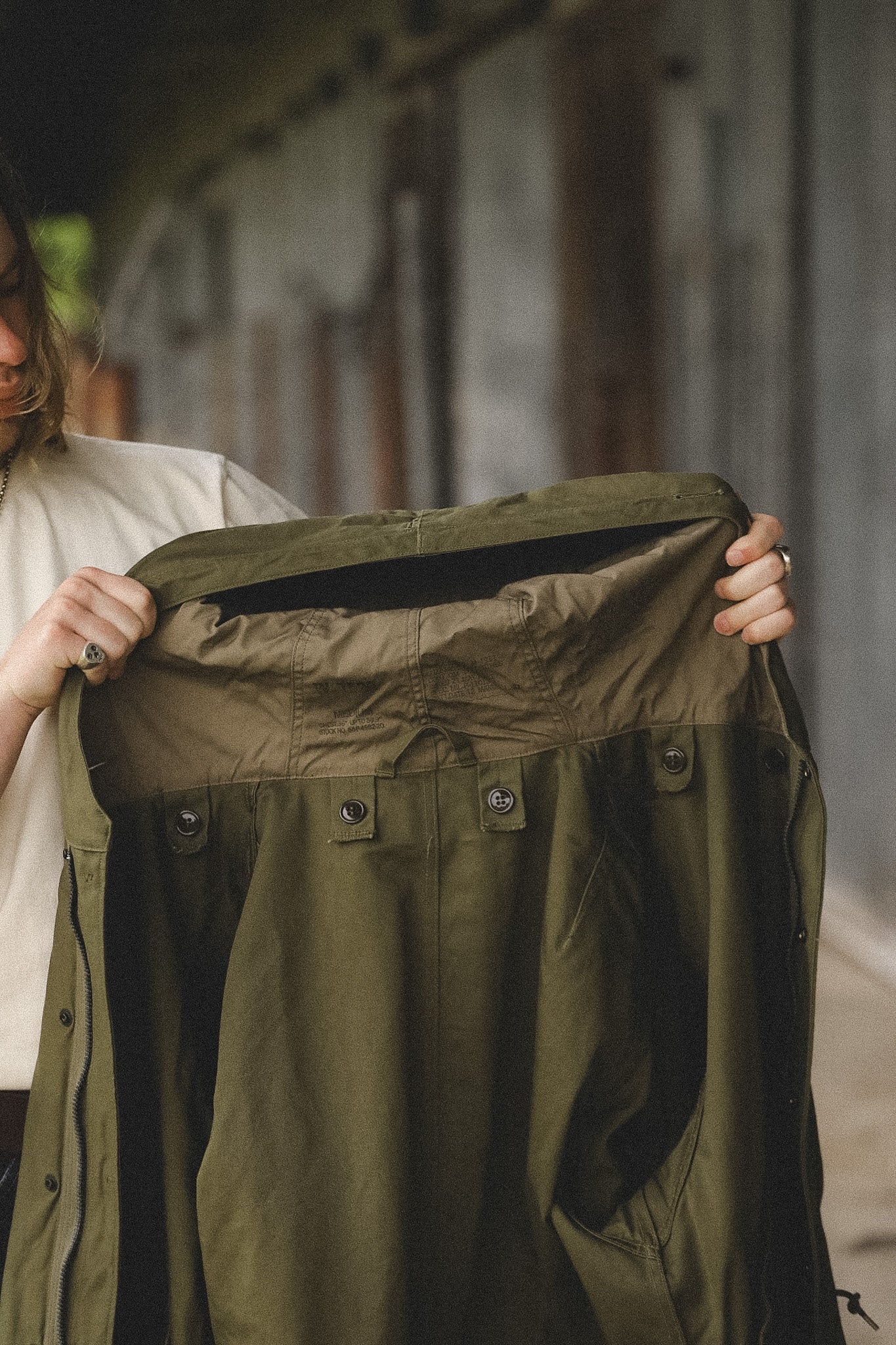 Person holding up a green jacket with a blurred background