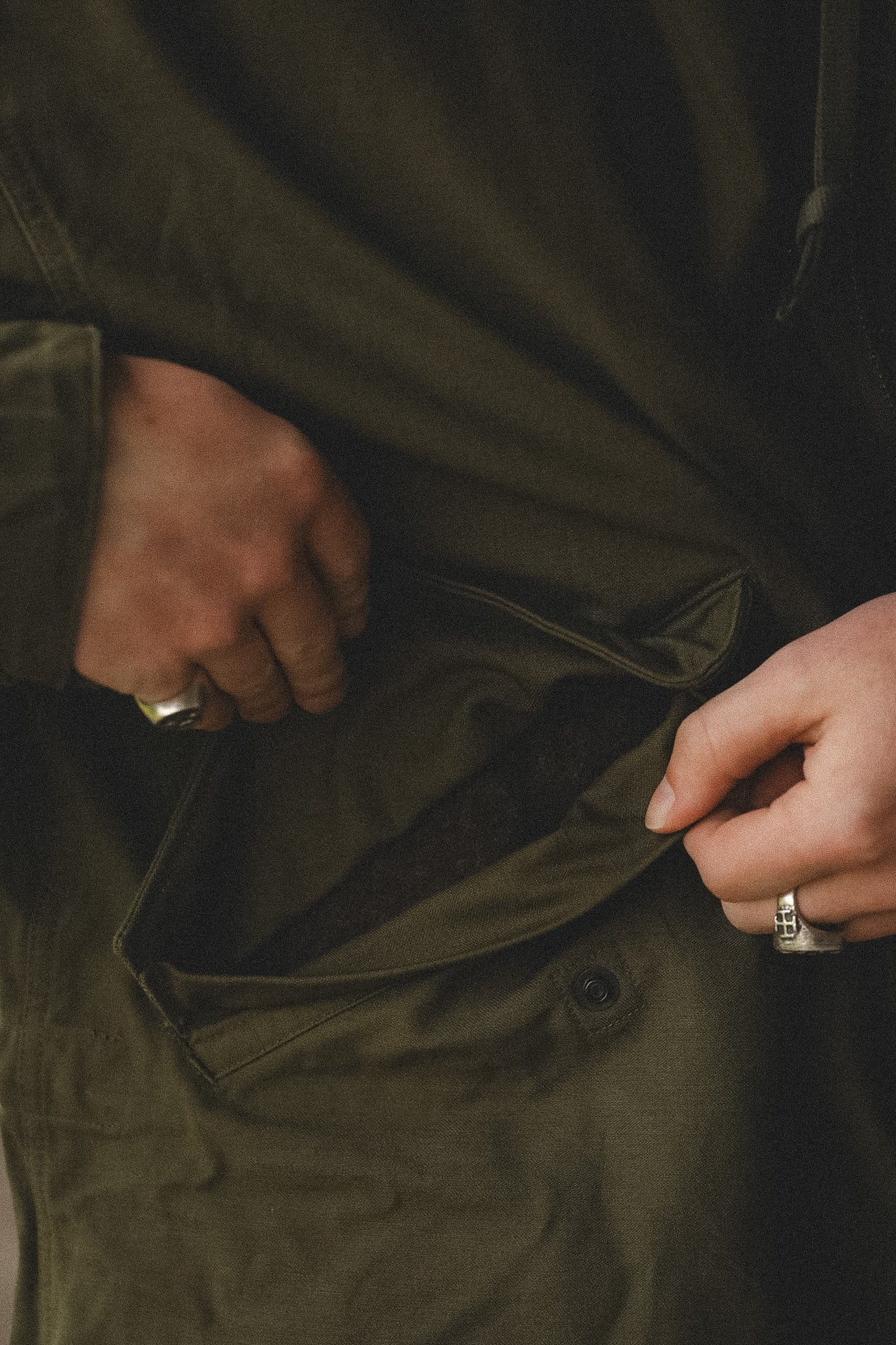 Person wearing a green jacket with a close-up of their hand and fingers.