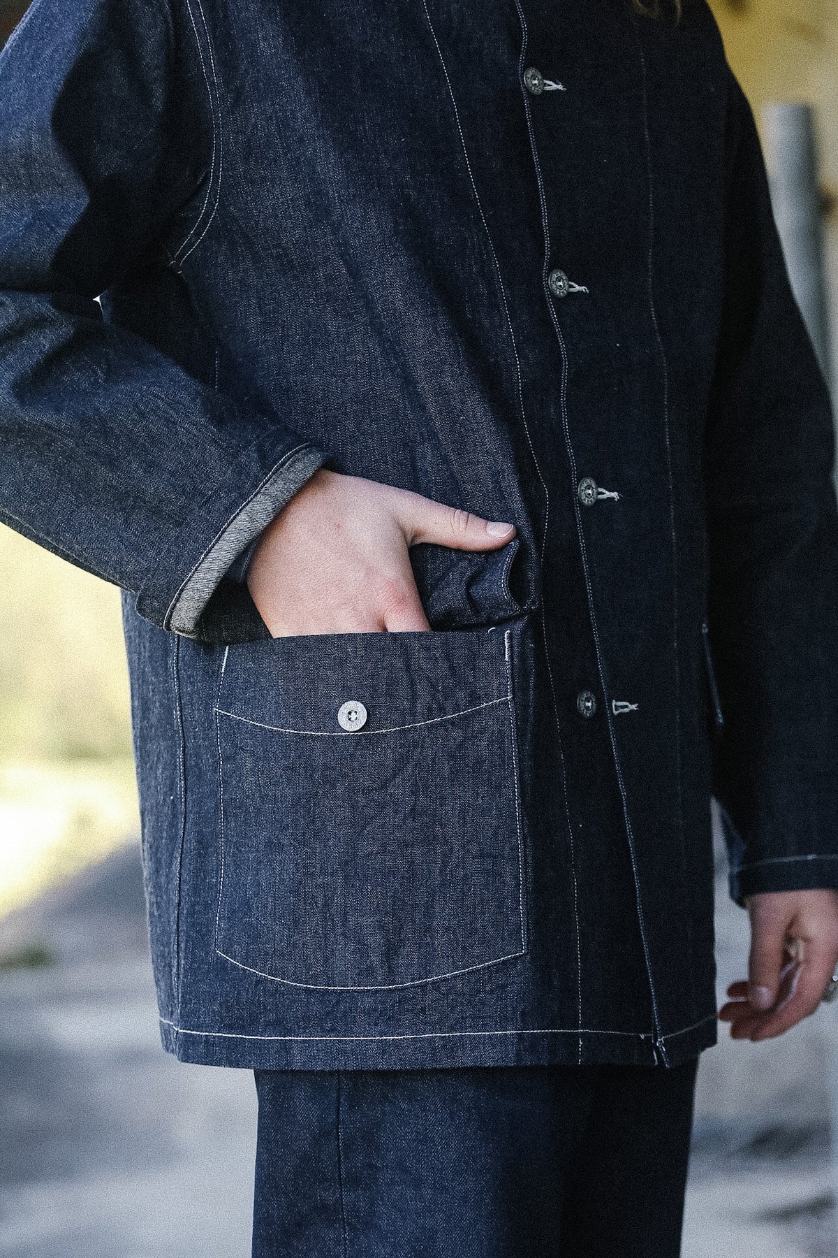Person wearing a dark denim jacket with a blurred background