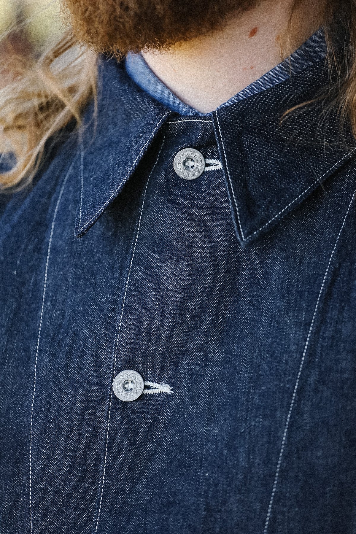 Close-up of a person wearing a dark denim shirt with buttons.