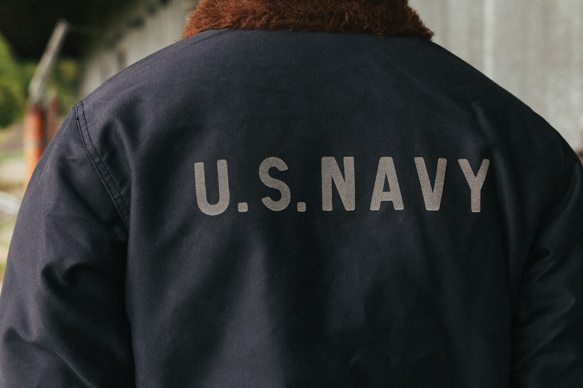 Back view of a person wearing a dark navy jacket with 'U.S.