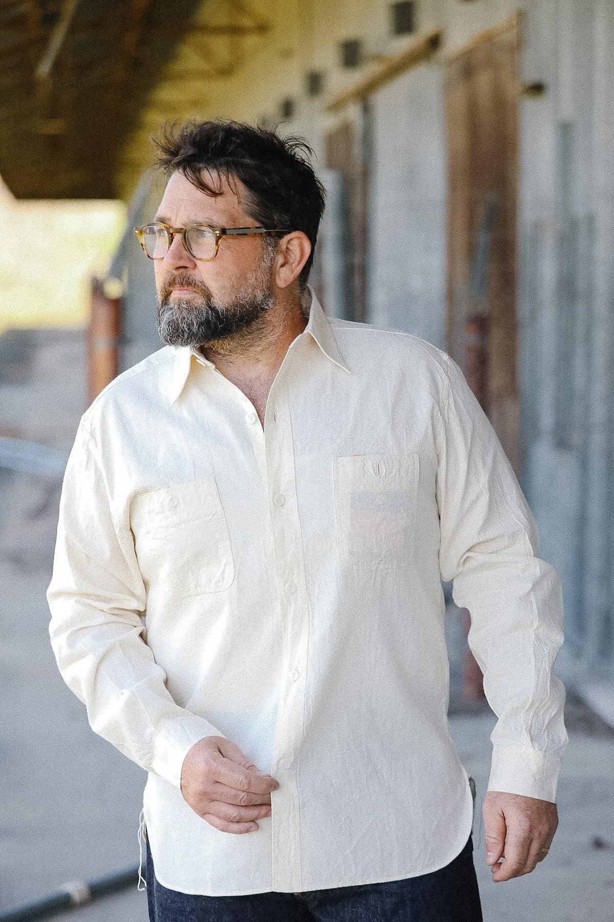 Man wearing a white shirt standing outdoors with a neutral background