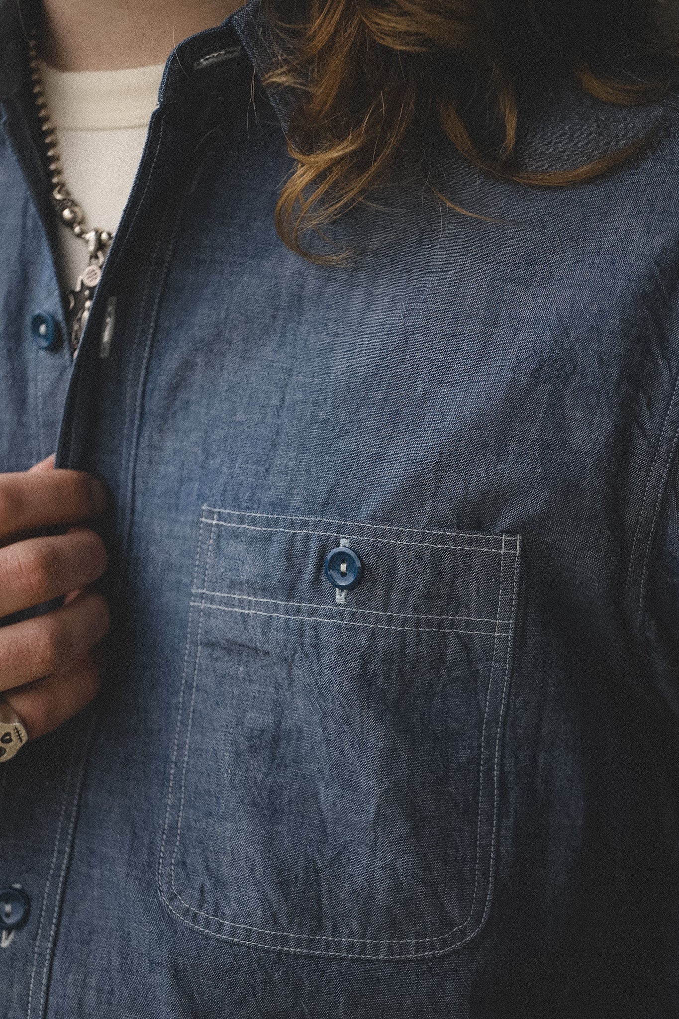 Close-up of a person wearing a blue denim shirt with a pocket.