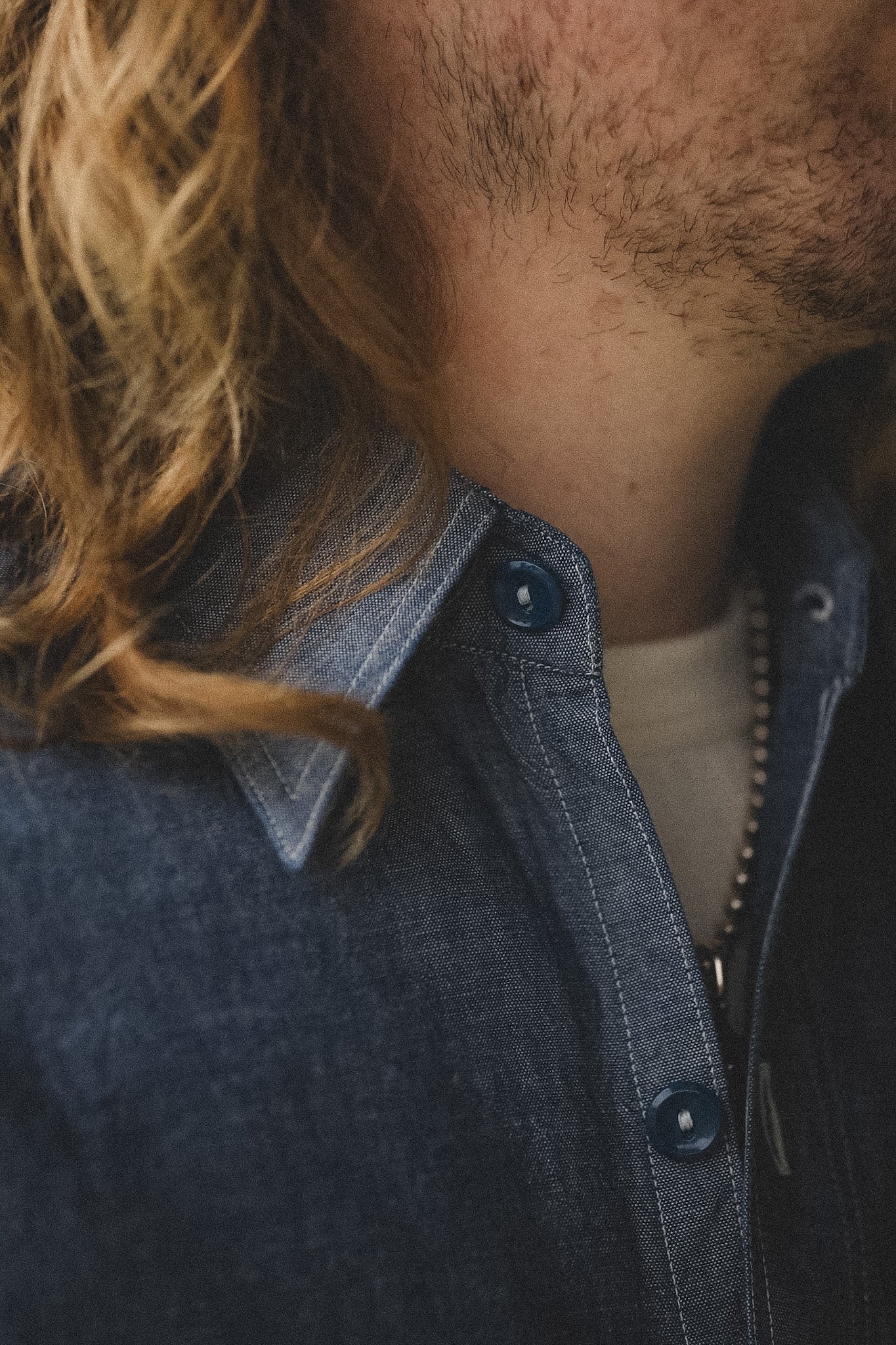 Close-up of a person wearing a dark denim jacket with a blurred background
