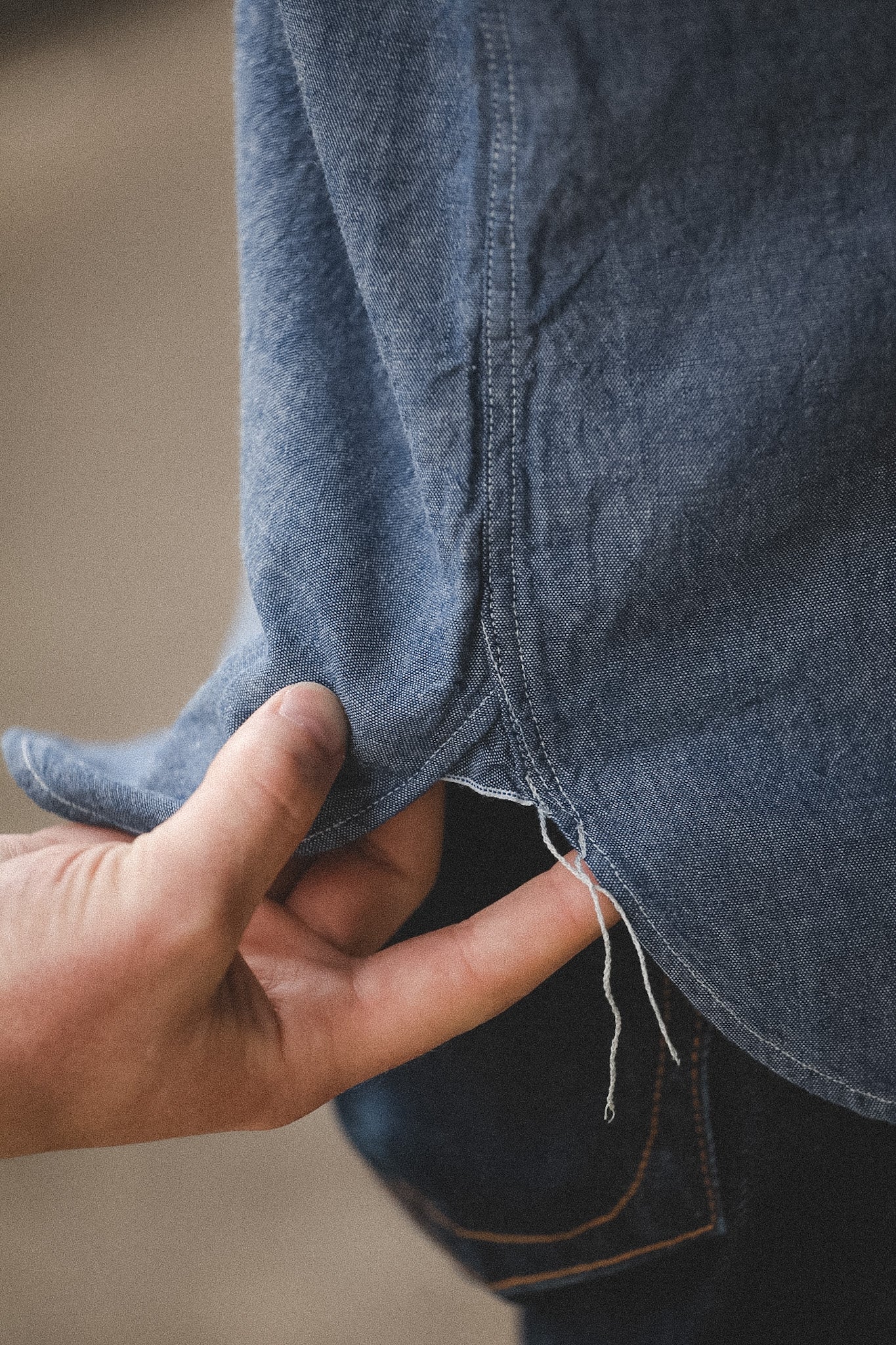 Close-up of a hand holding a blue denim fabric with a blurred background