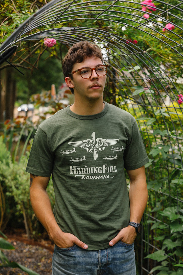 Man wearing a green t-shirt with 'Harding Field Louisiana' design in an outdoor setting.