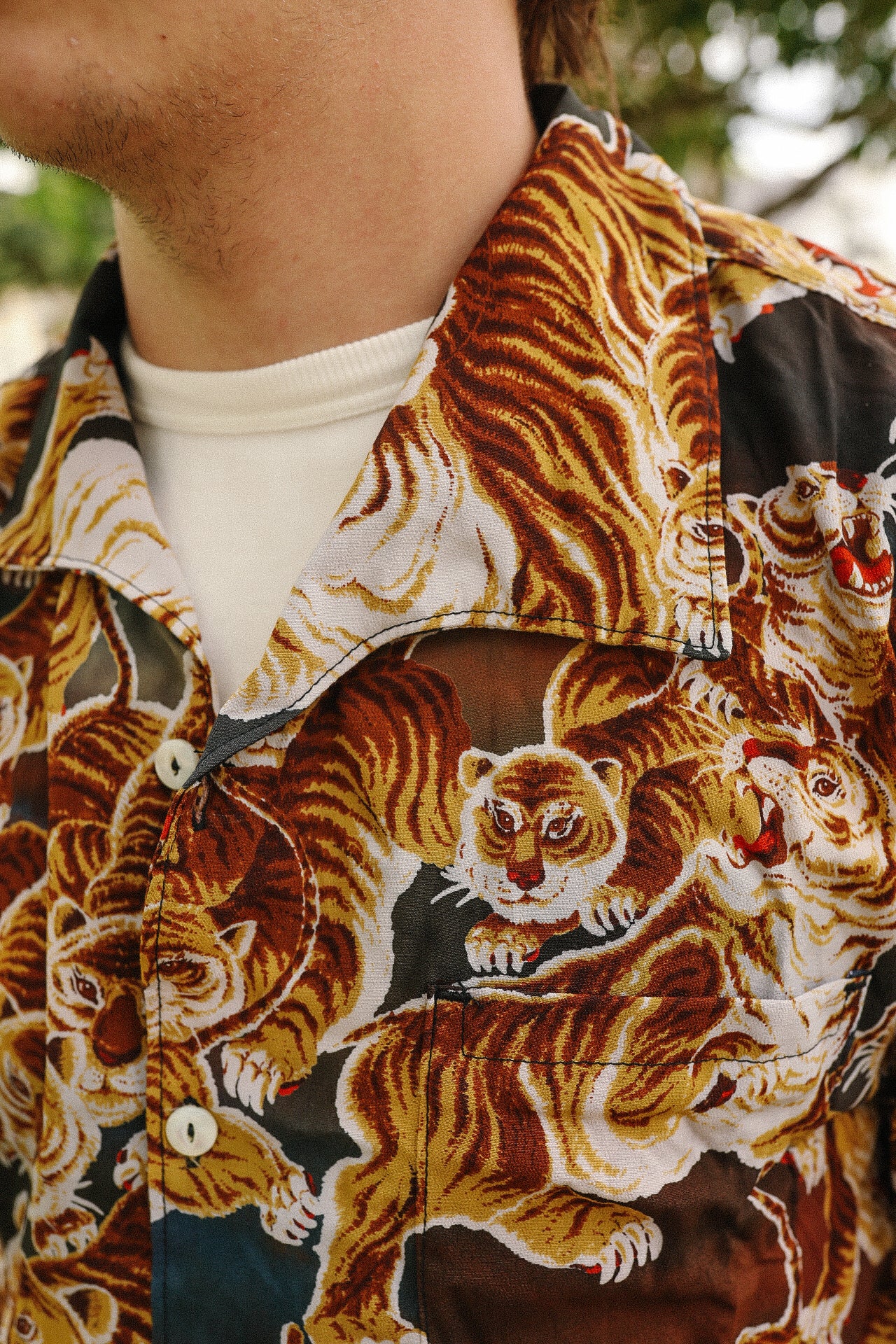 Close-up of a shirt collar with bold tiger print design featuring orange and white tigers, worn over a white shirt