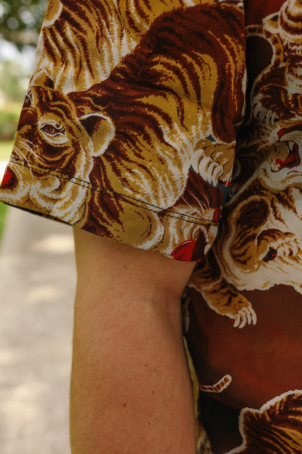 Close-up of a brown shirt sleeve with detailed painted tiger print on fabric at Iron Shop Provisions