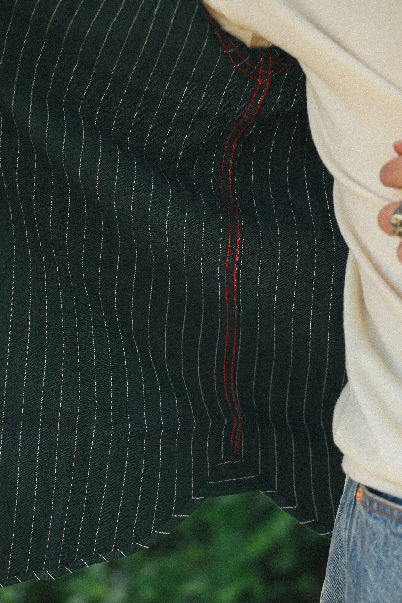 Close-up of green striped Coke Stripe embroidered short sleeve work shirt with red stitching detail
