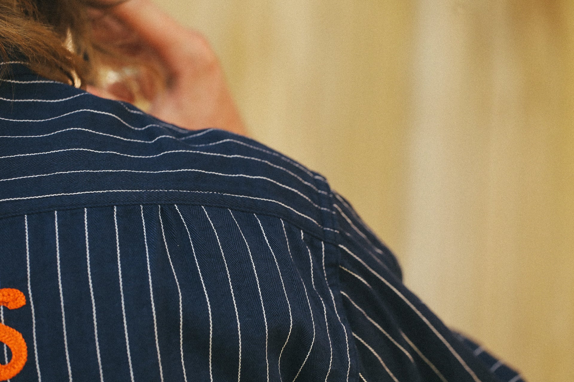 Close-up of navy blue striped work shirt with orange embroidered text on shoulder