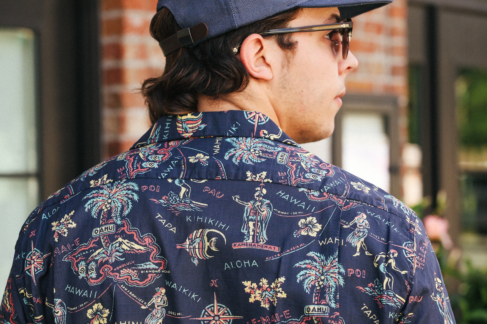 Man wearing navy cotton linen Hawaiian shirt with colorful island prints and illustrations