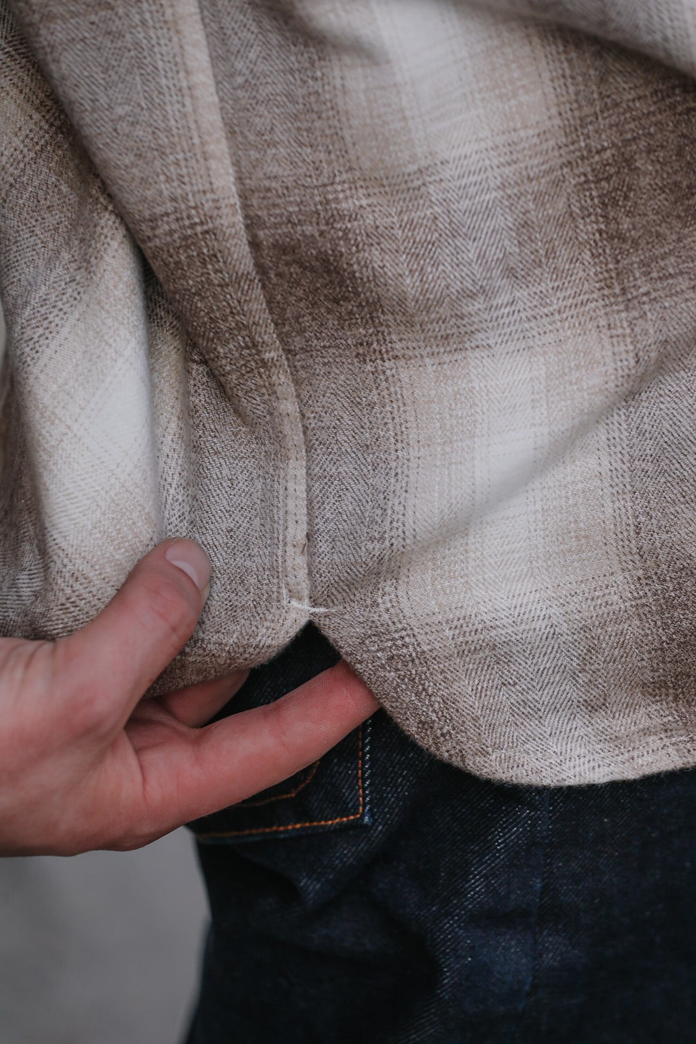 Close-up of a hand holding a plaid fabric with a neutral color palette.