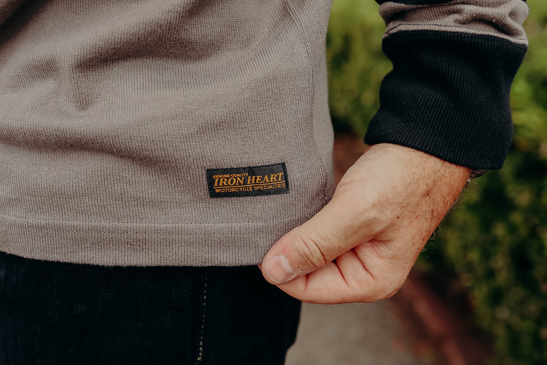 Close-up of Iron Heart motorcycle sweatshirt label on taupe fabric with black cuff seen outdoors