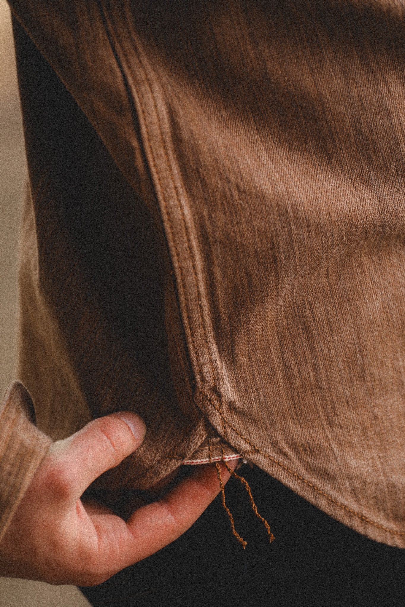 Close-up of a brown fabric with a hand holding it, blurred background