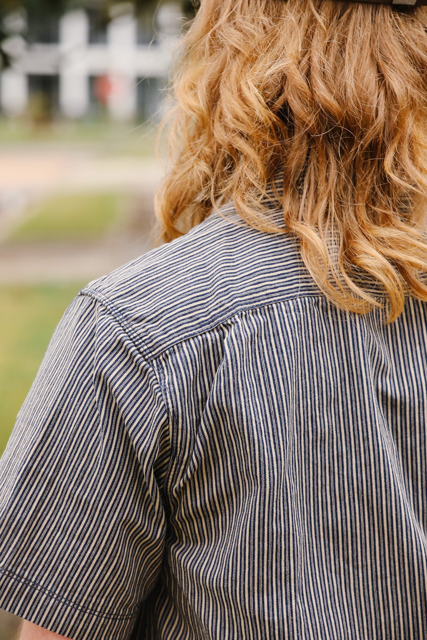 Person wearing a striped shirt with a blurred outdoor background