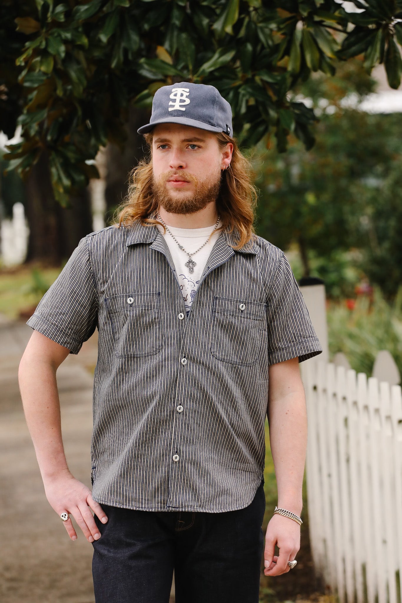 Man with long hair wearing a checkered shirt and cap outdoors