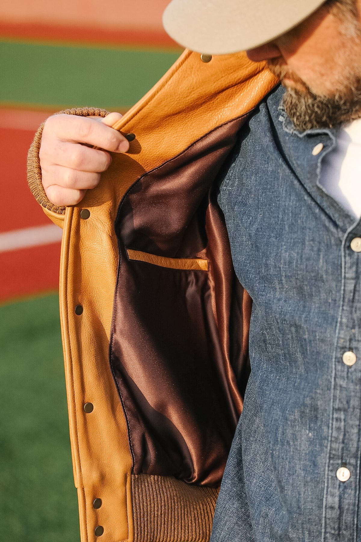 Person wearing a tan leather jacket with a brown lining, standing outdoors.