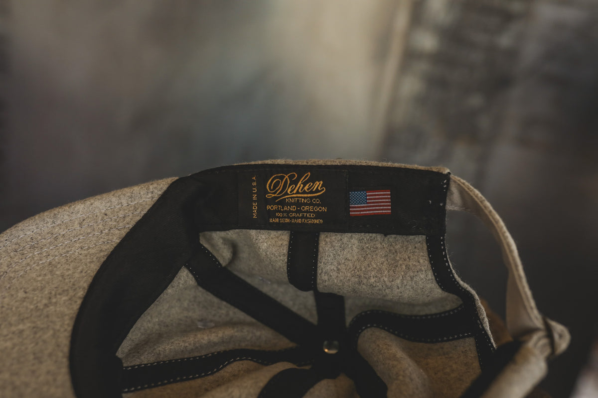 Close-up of the interior crown of a textured beige cap, showing a black fabric band with gold 'Dohen' branding, an American flag patch, and black adjustable straps.