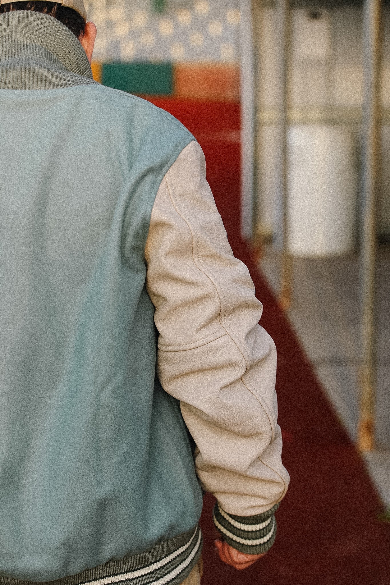 Person wearing a two-tone jacket with a blurred indoor background
