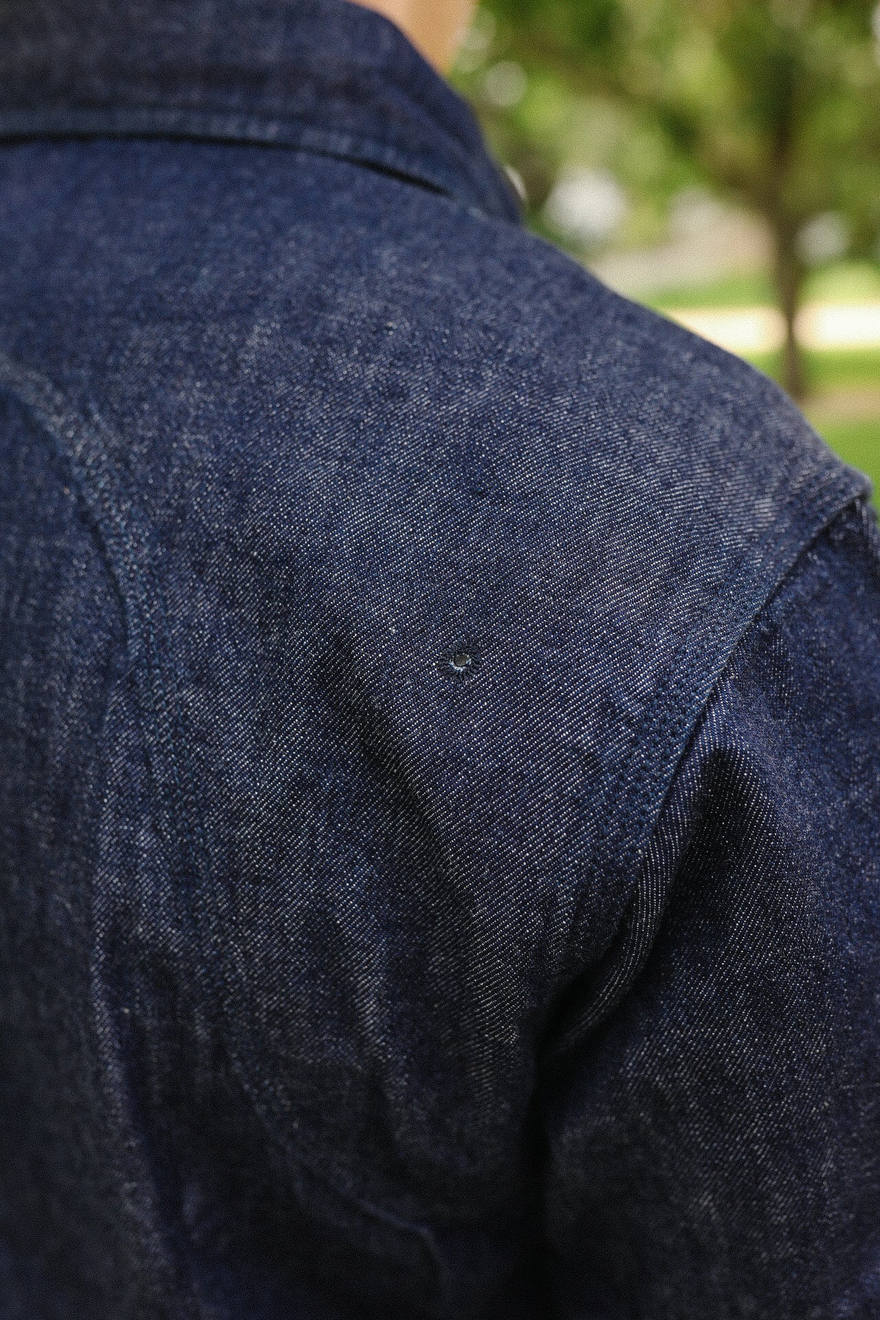 Close-up of indigo denim medical shirt shoulder with detailed stitching and vent hole by Iron Shop Provisions