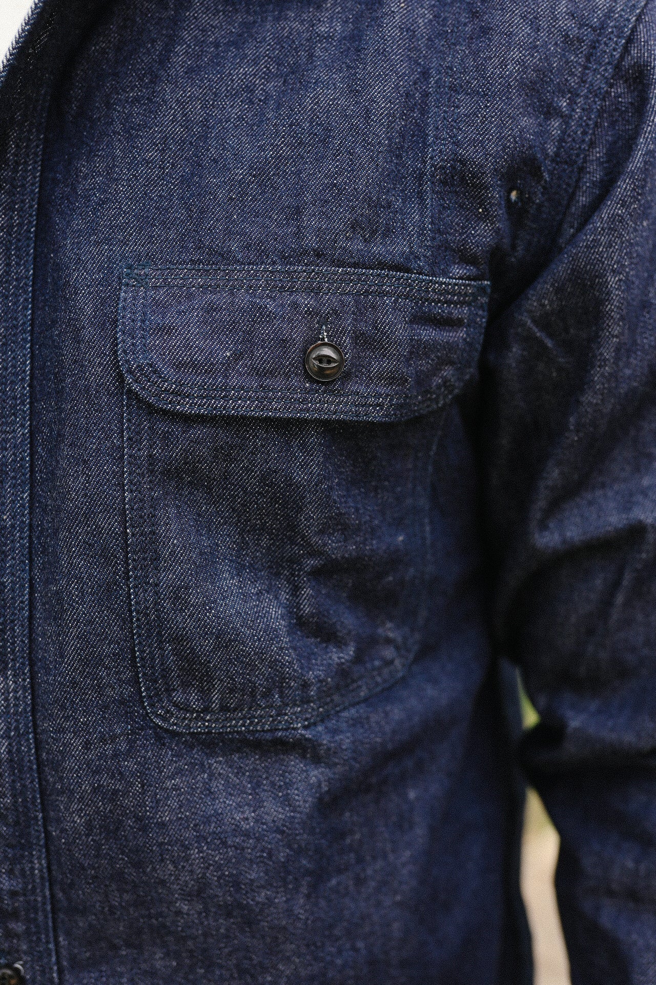 Close-up of Indigo denim medical shirt pocket with black button detail