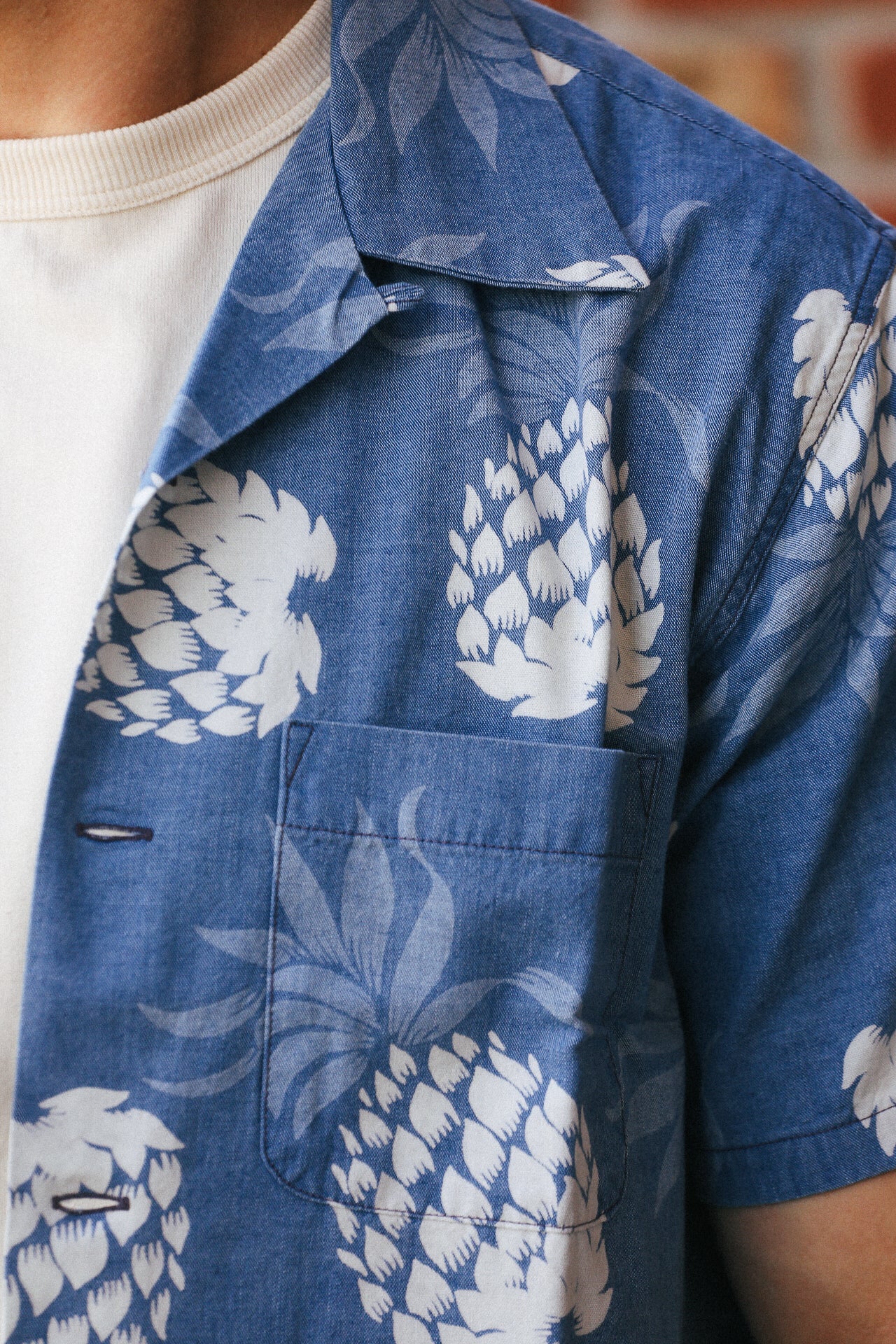 Close-up of Indigo cotton Hawaiian shirt with white pineapple print and chest pocket over white t-shirt