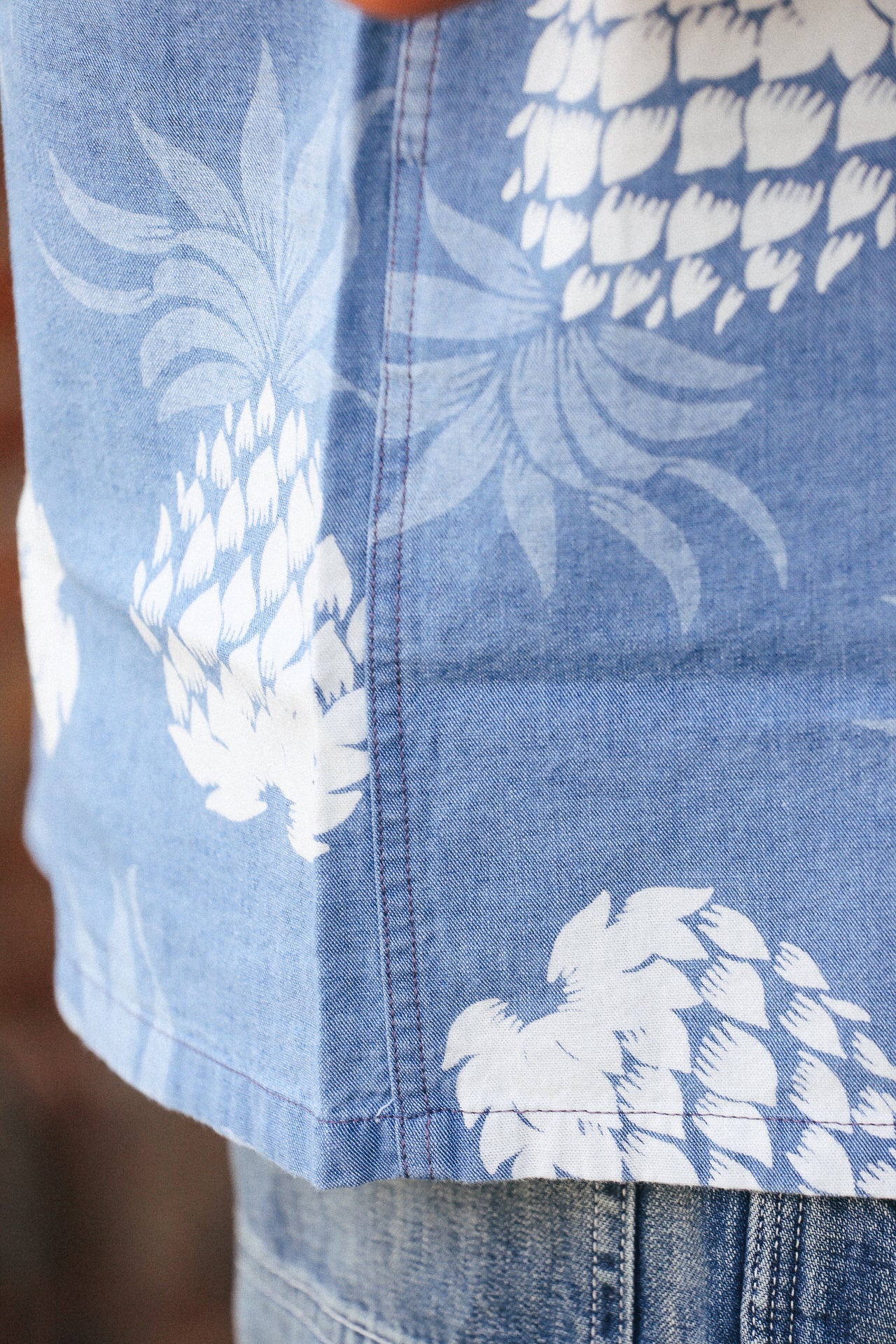 Close-up of Duke Kahanamoku indigo cotton Hawaiian shirt with white pineapple print and visible side seam stitching