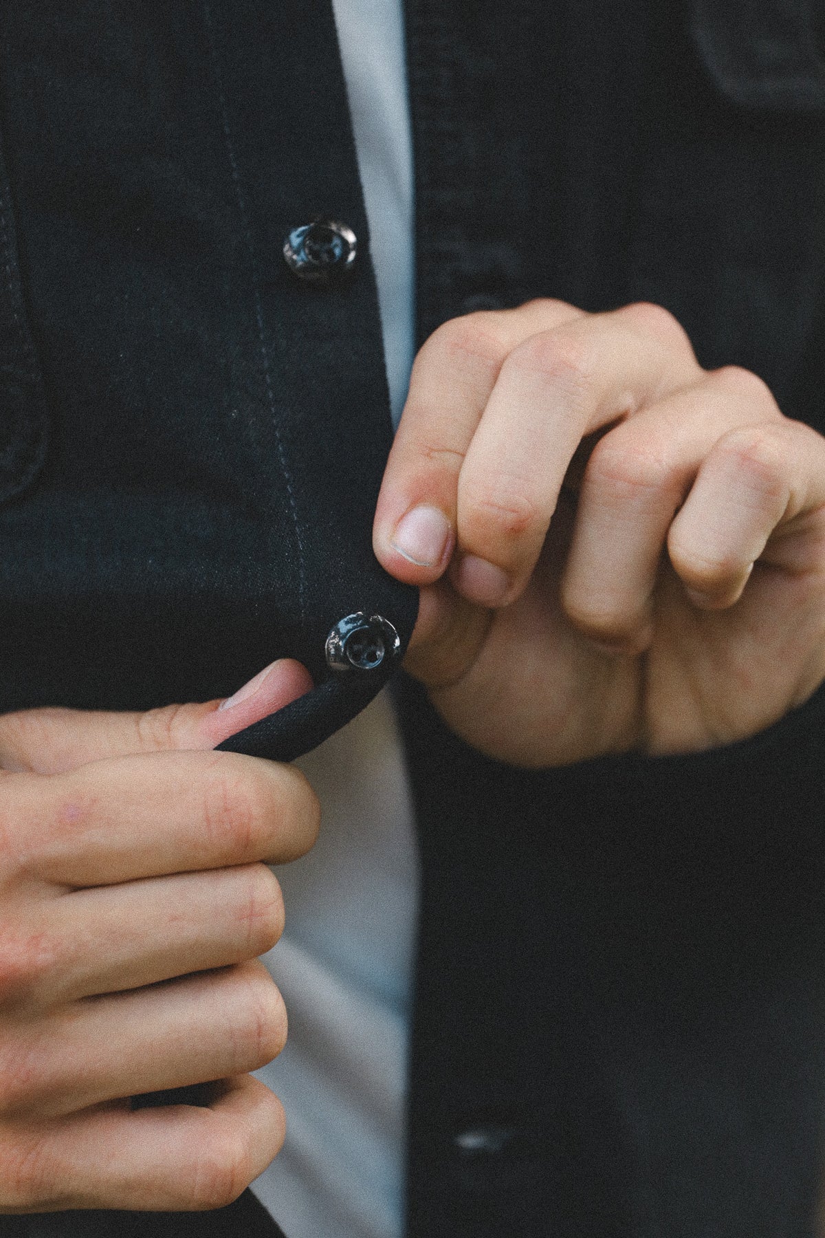 Close-up of hands holding a small object against a dark background