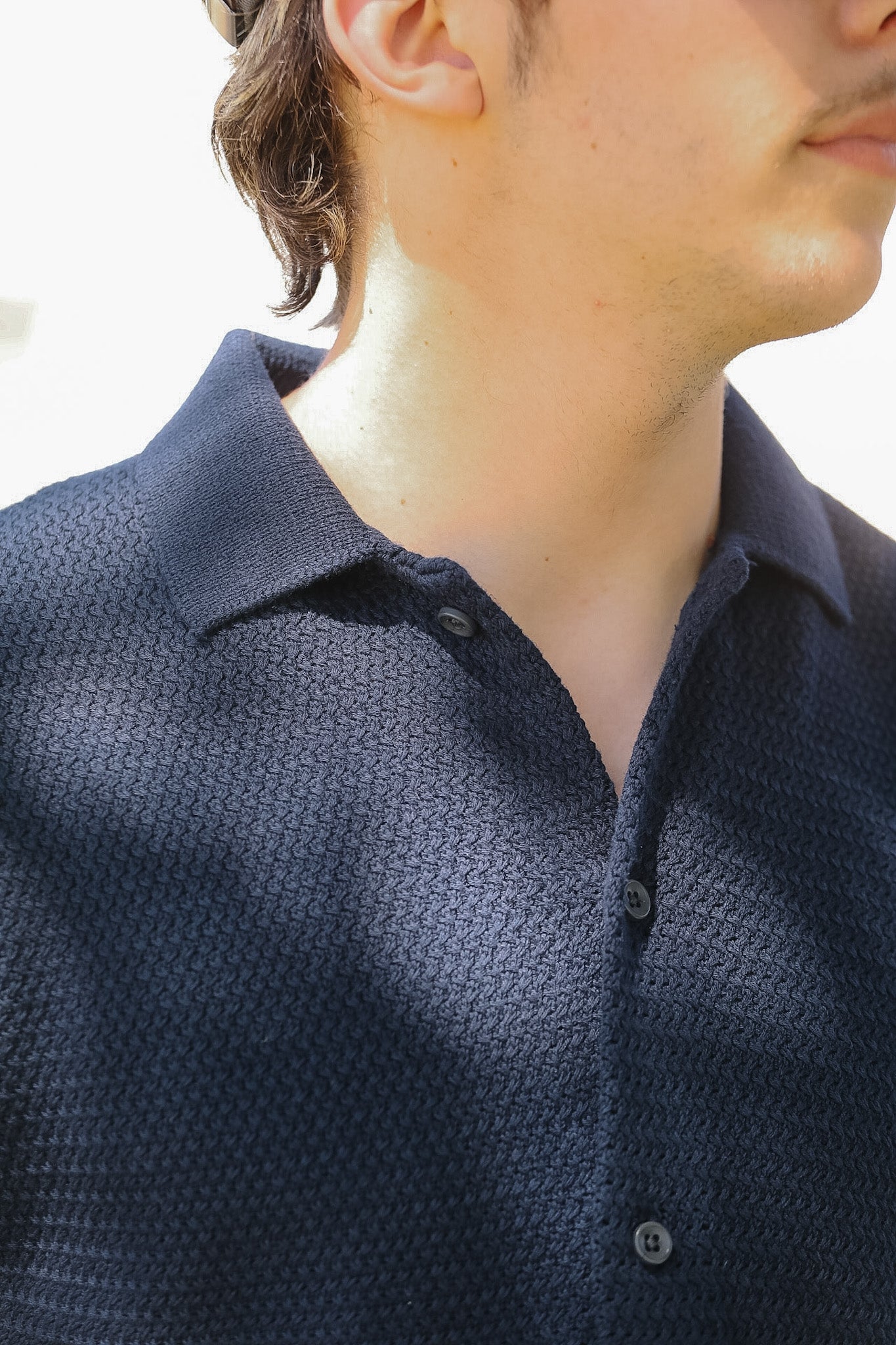 Close-up of a person wearing a dark blue textured shirt with a blurred background