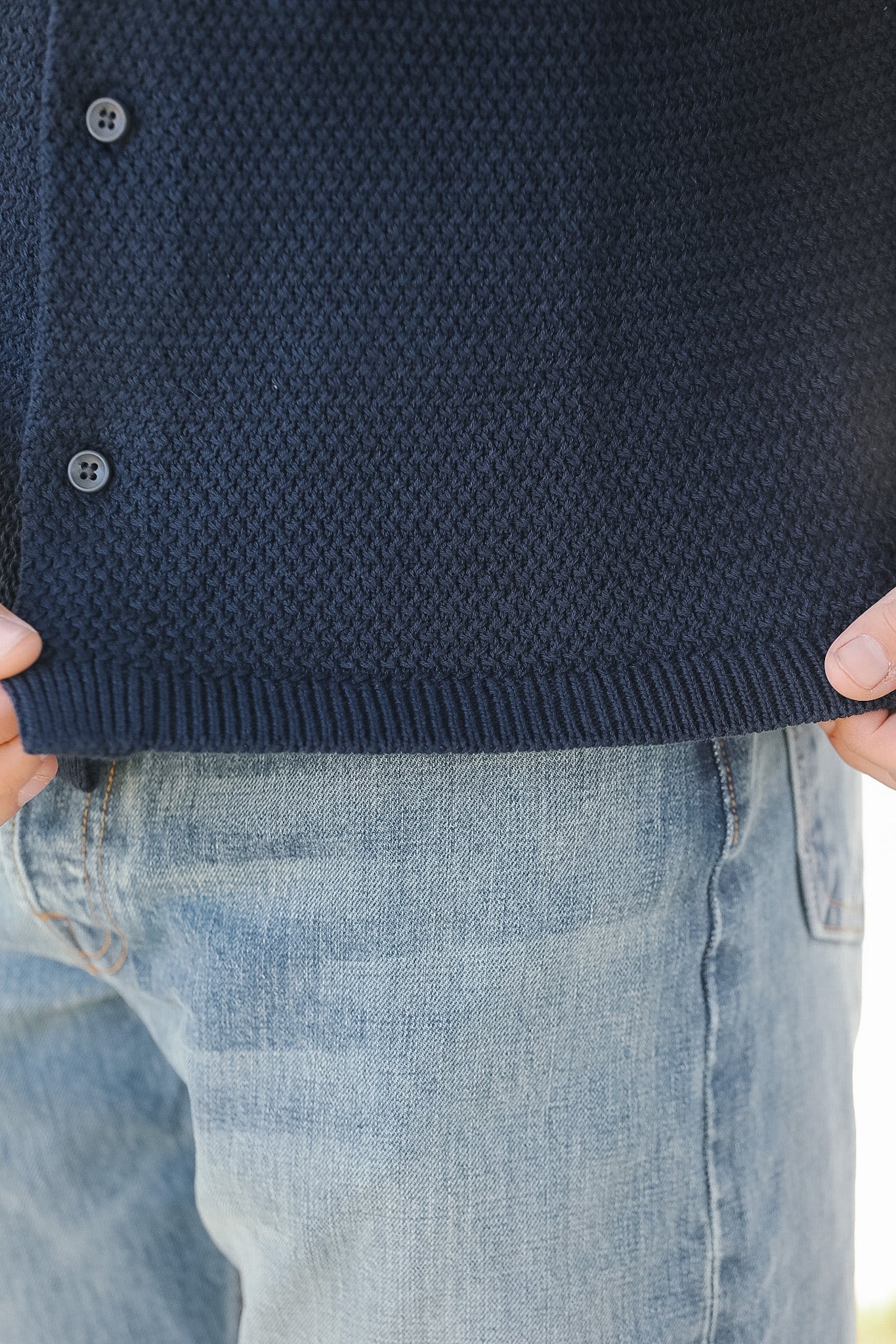 Navy blue textured cardigan worn by a person, with a blurred background