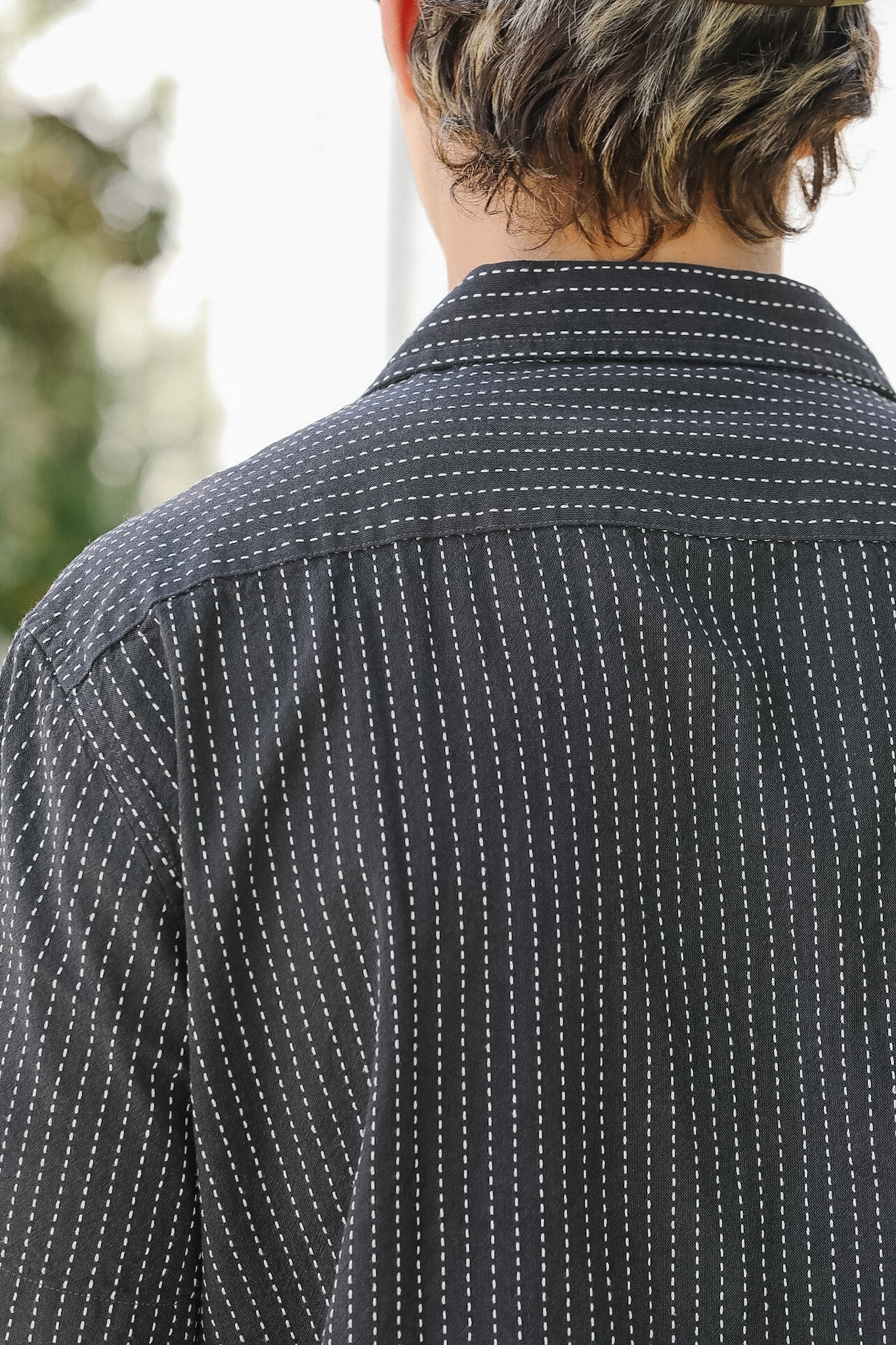 Person wearing a black and white patterned shirt with blurred background