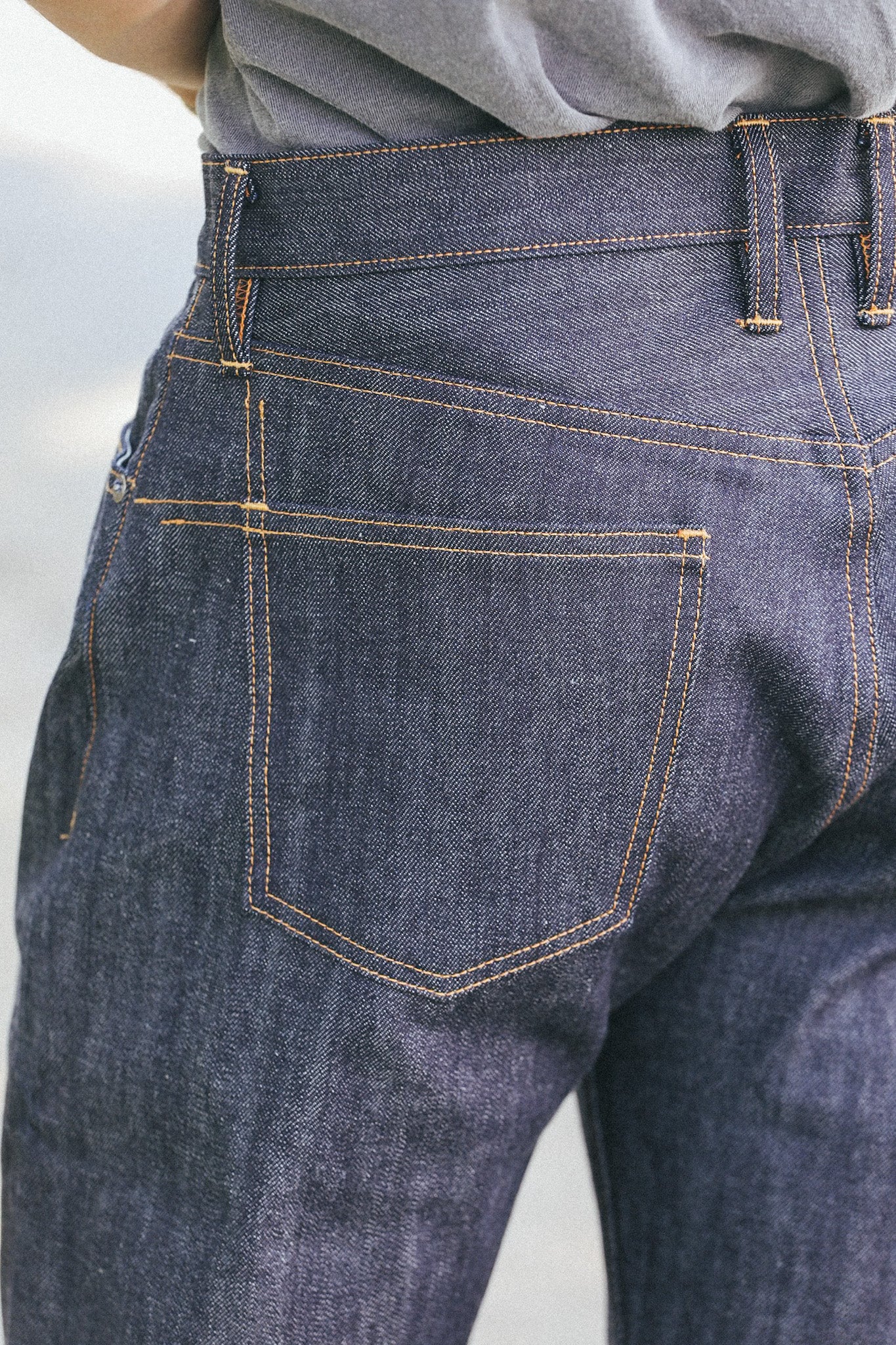Close-up of dark blue denim jeans with orange stitching pocket detail from Iron Shop Provisions