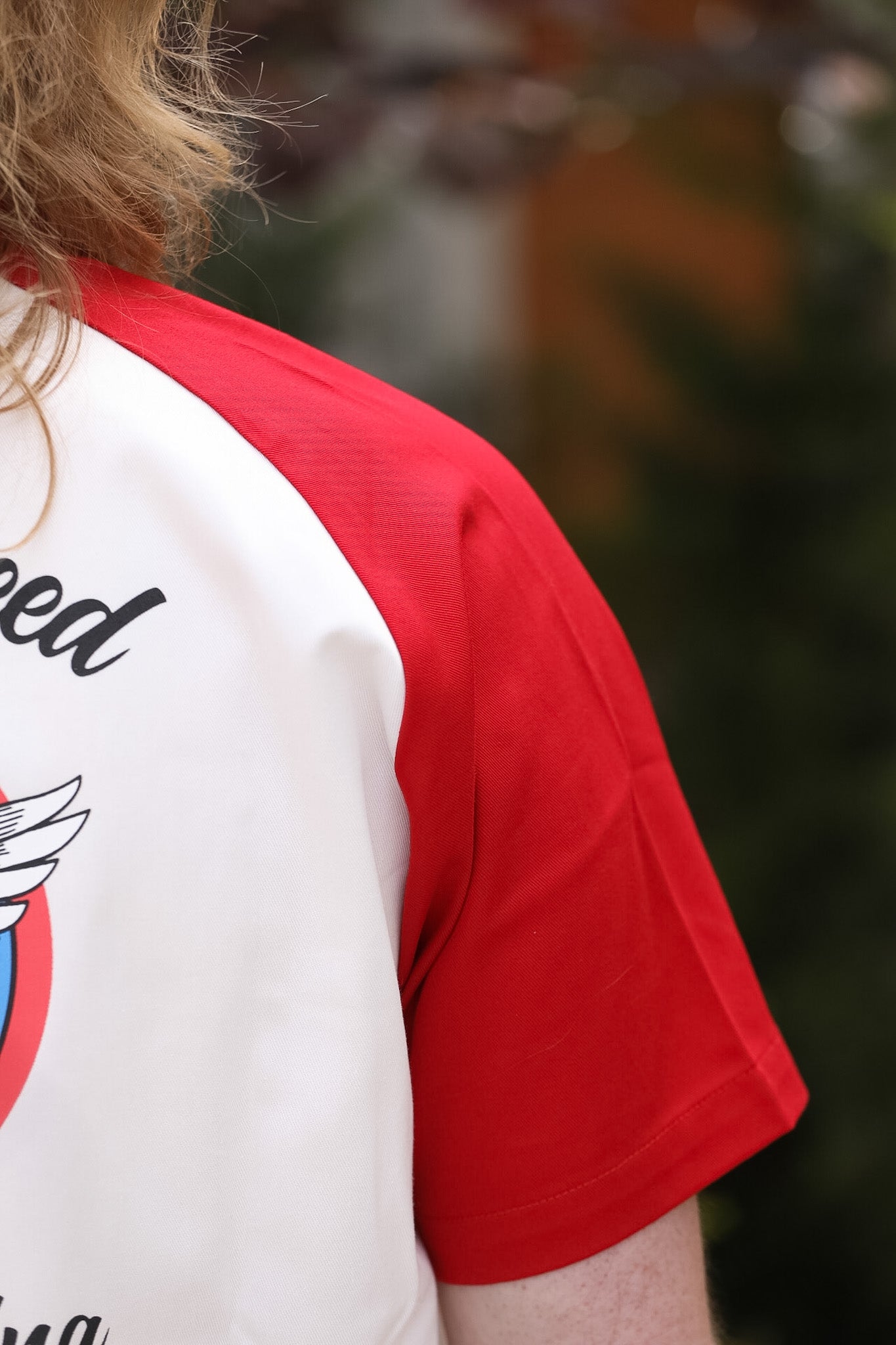 Person wearing a red and white baseball shirt with text and graphics.
