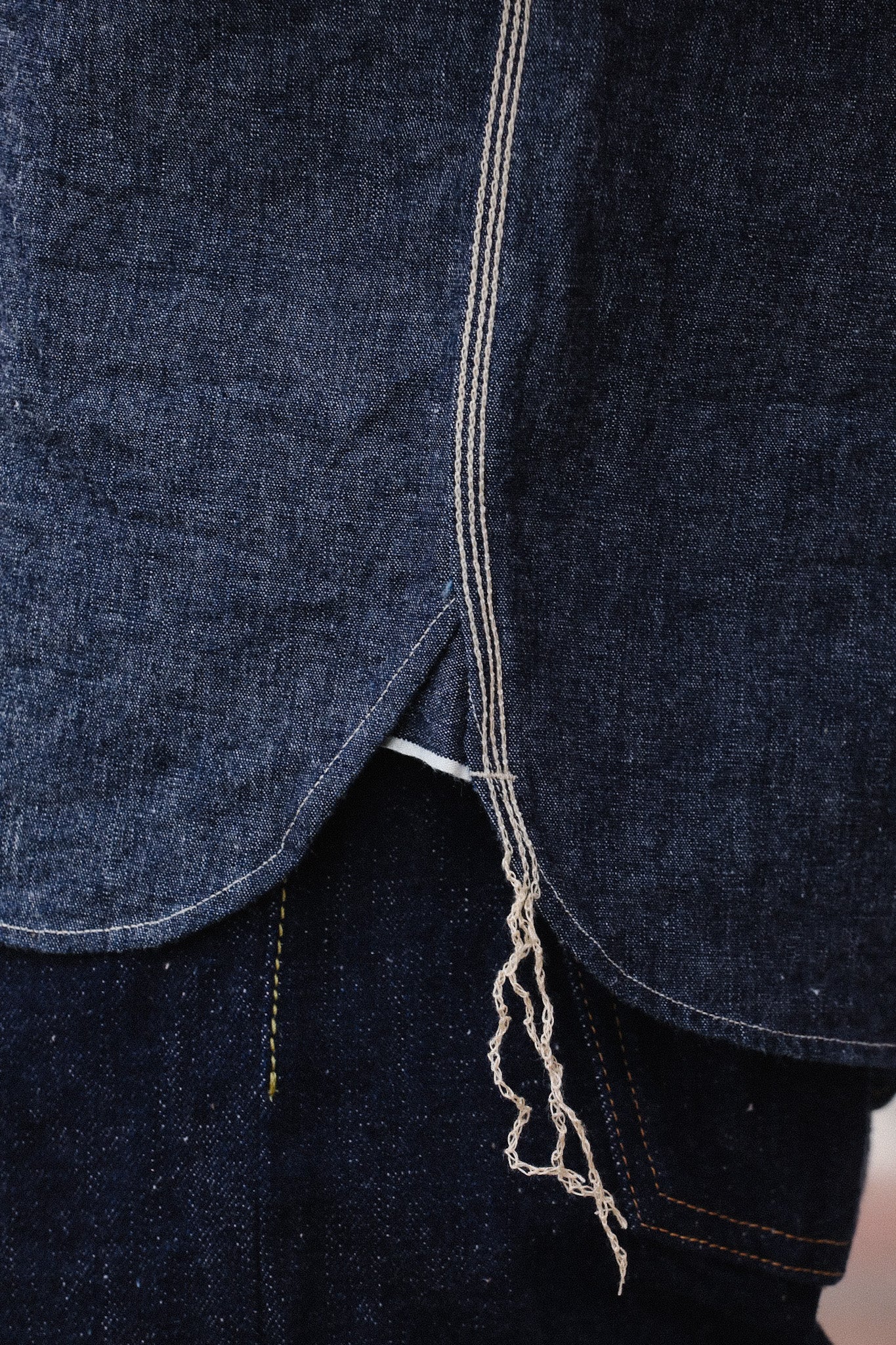 Close-up of dark blue denim fabric with white selvedge edge and frayed thread detail on Iron Shop Provisions jeans