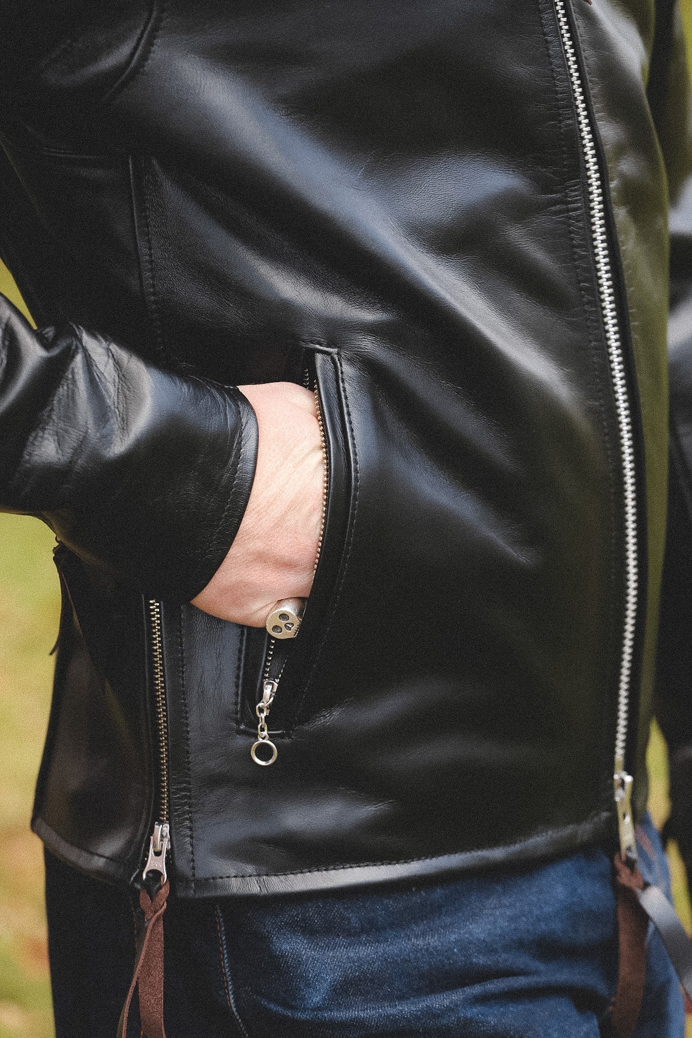 A person wearing a black horsehide rider's jacket with a collar, standing outdoors.