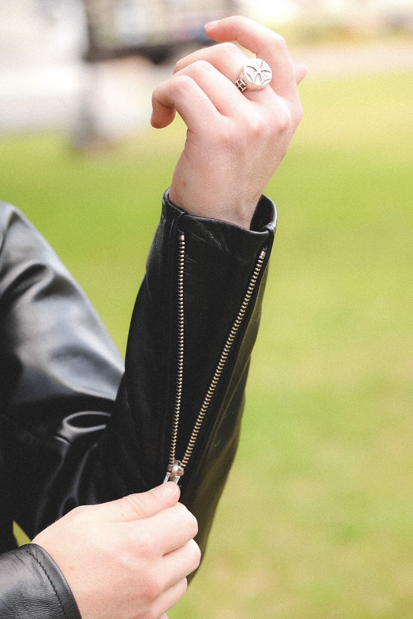 A person wearing a black horsehide rider's jacket with a collar, standing outdoors.