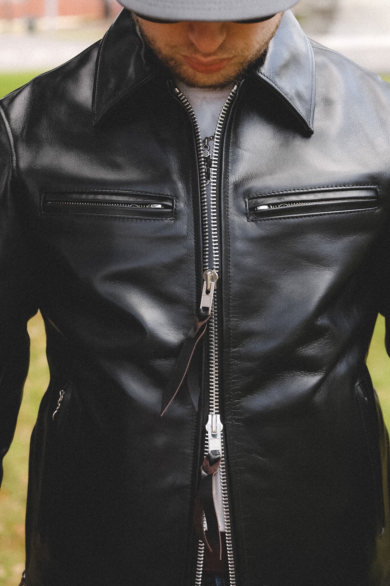 A person wearing a black horsehide rider's jacket with a collar, standing outdoors.