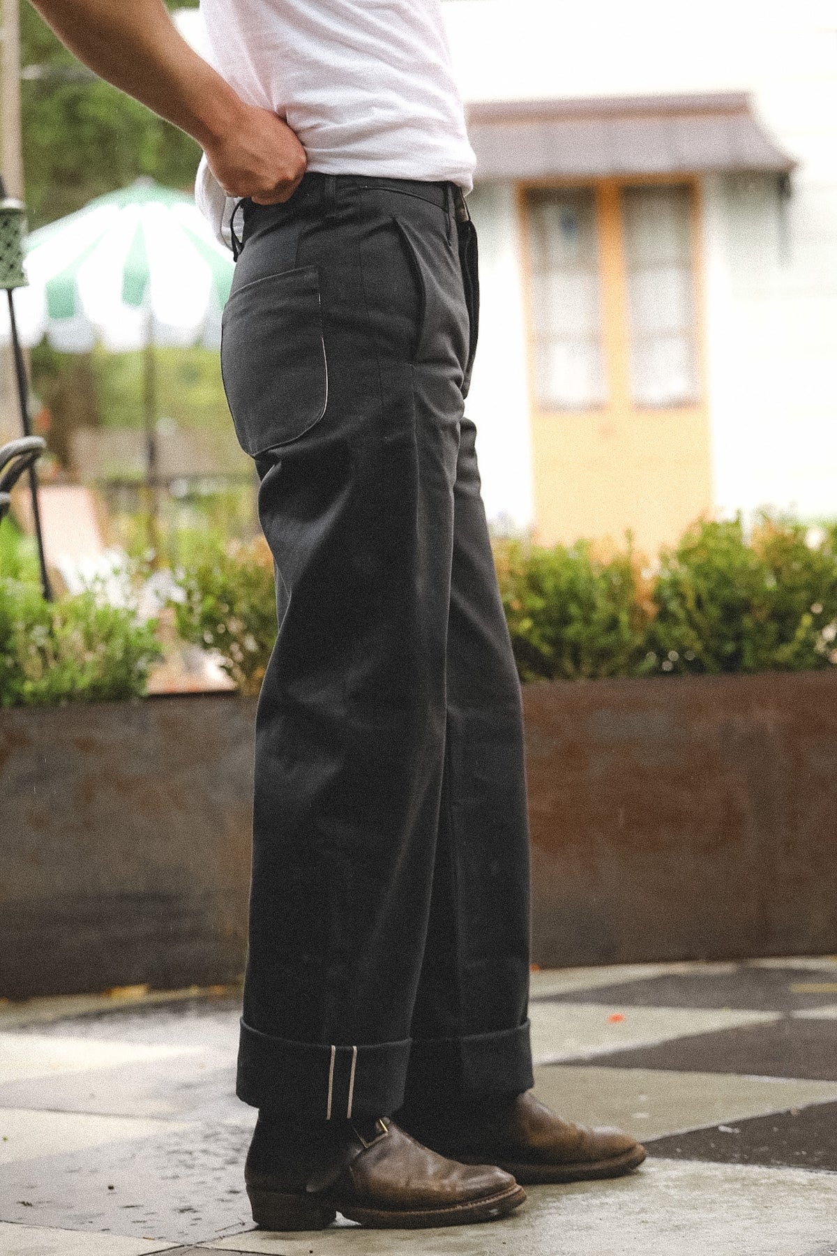 Person wearing dark pants and a white shirt outdoors with blurred background