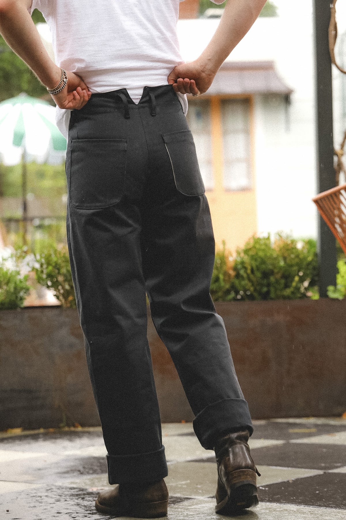 Person wearing dark pants and a white shirt with a blurred outdoor background