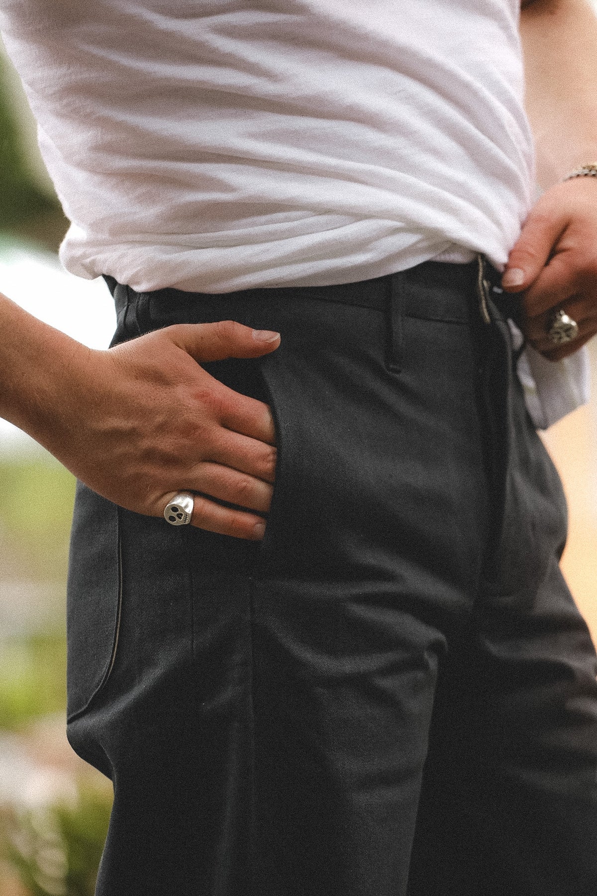 Person wearing a white shirt and dark pants with a blurred background