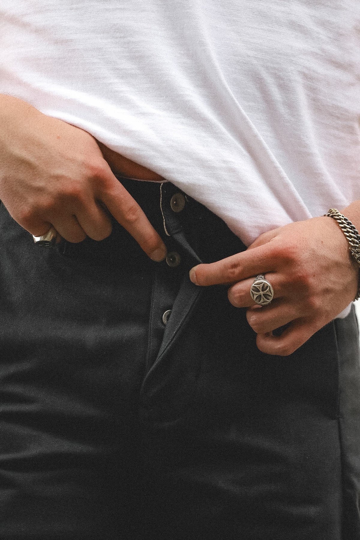 Person buttoning a black jacket with a white shirt underneath