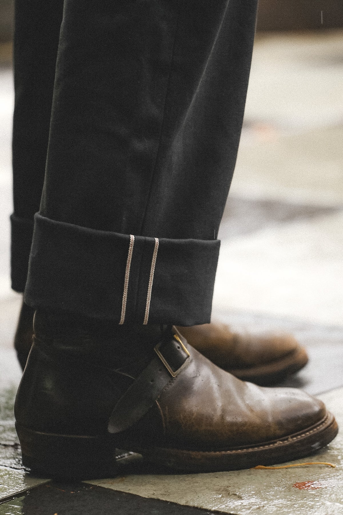 Close-up of brown leather shoes with black gaiters on a blurred background