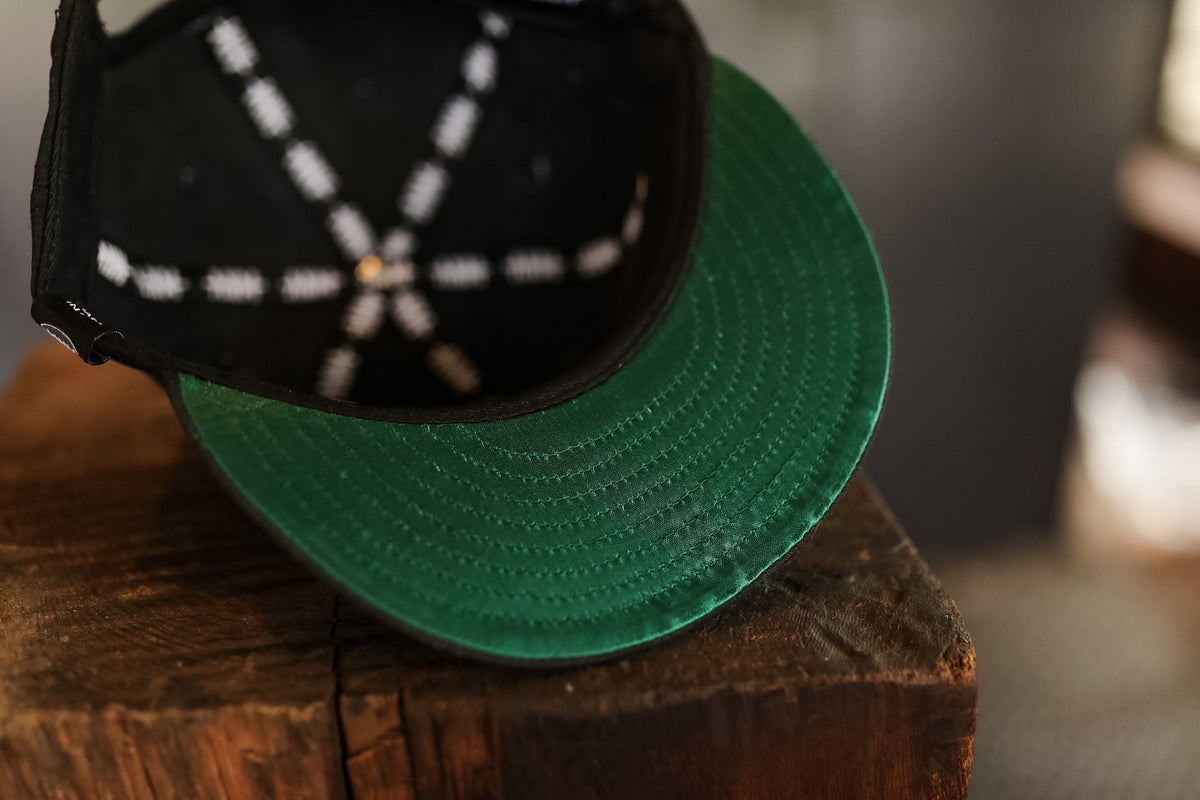 Green cap with black visor on a wooden surface