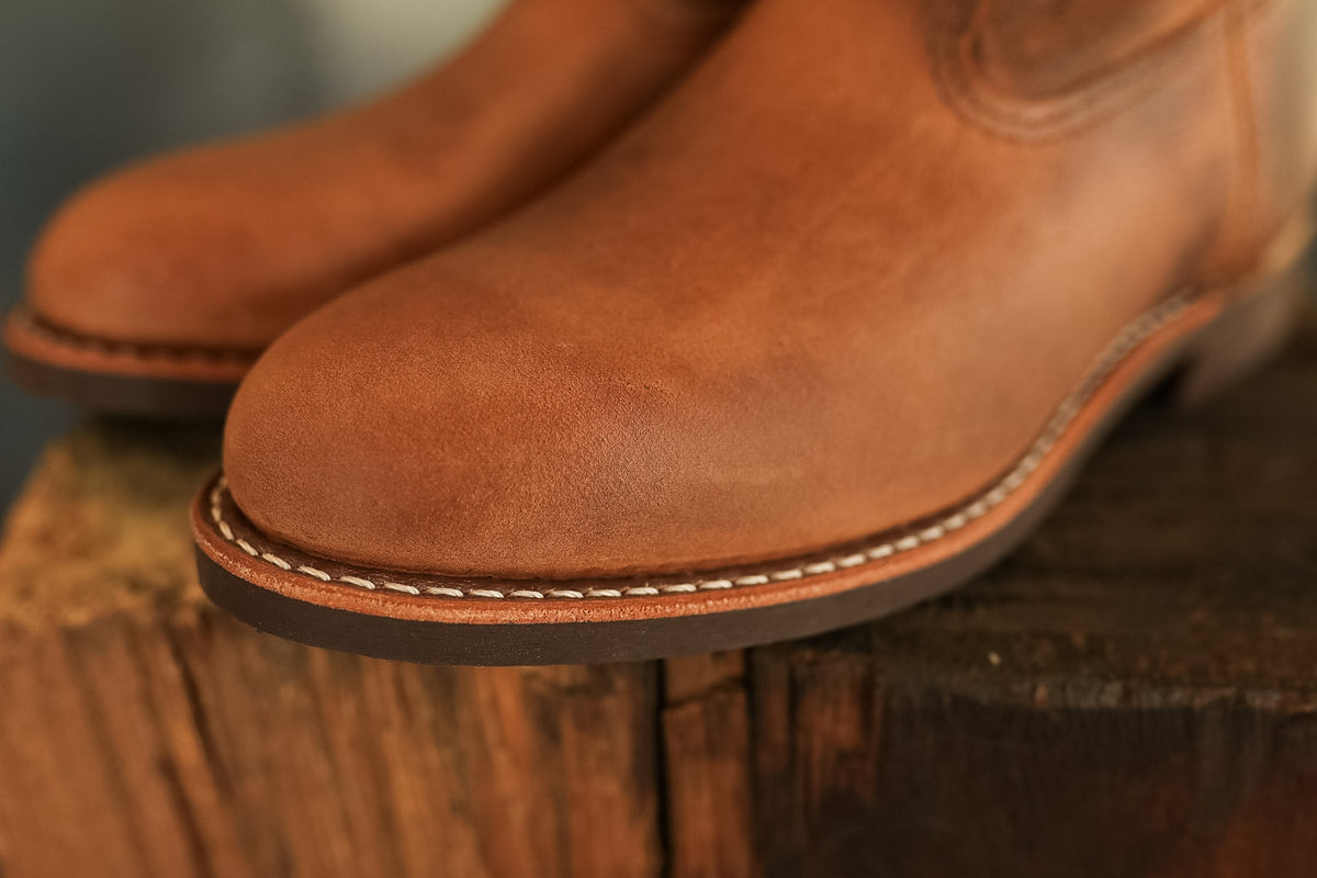 Pair of brown leather boots on a wooden block with a blurred background