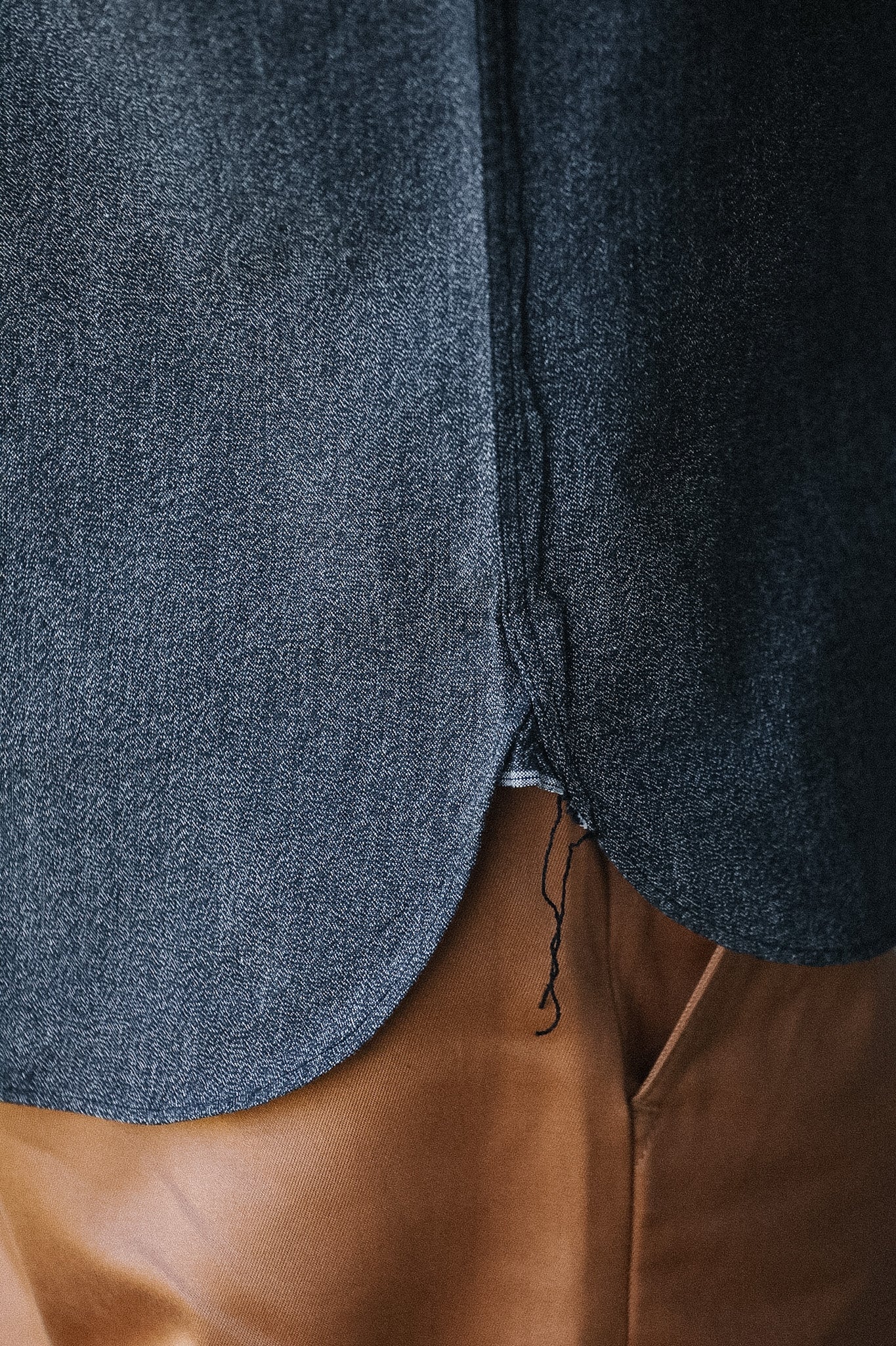 Close-up of a blue textured fabric garment with brown leather.
